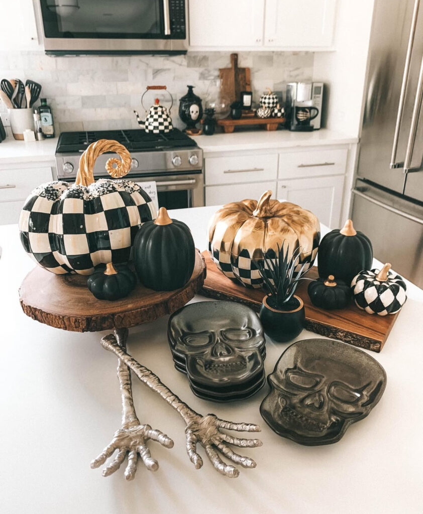 Checkerboard, black, and metallic pumpkins on wood slabs with stacked skull plates and skeleton salad tongs.