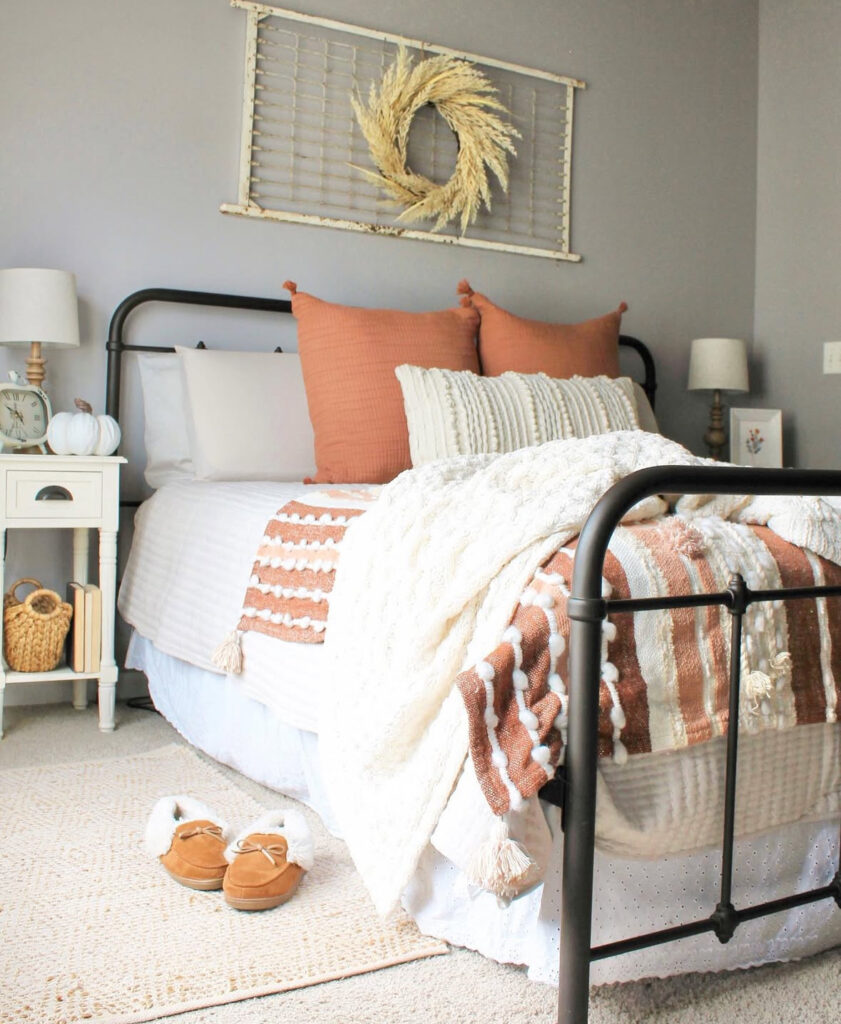 Metal bed with terracotta pillows, textured throws and grain wreath — bedroom ideas for fall.