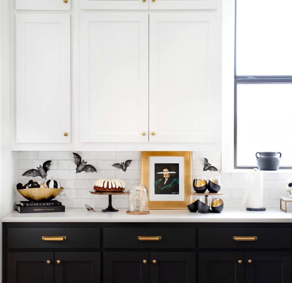 Matte bats swooping along the backsplash, a gold-framed print, cake stand, and cloche-covered skeleton.