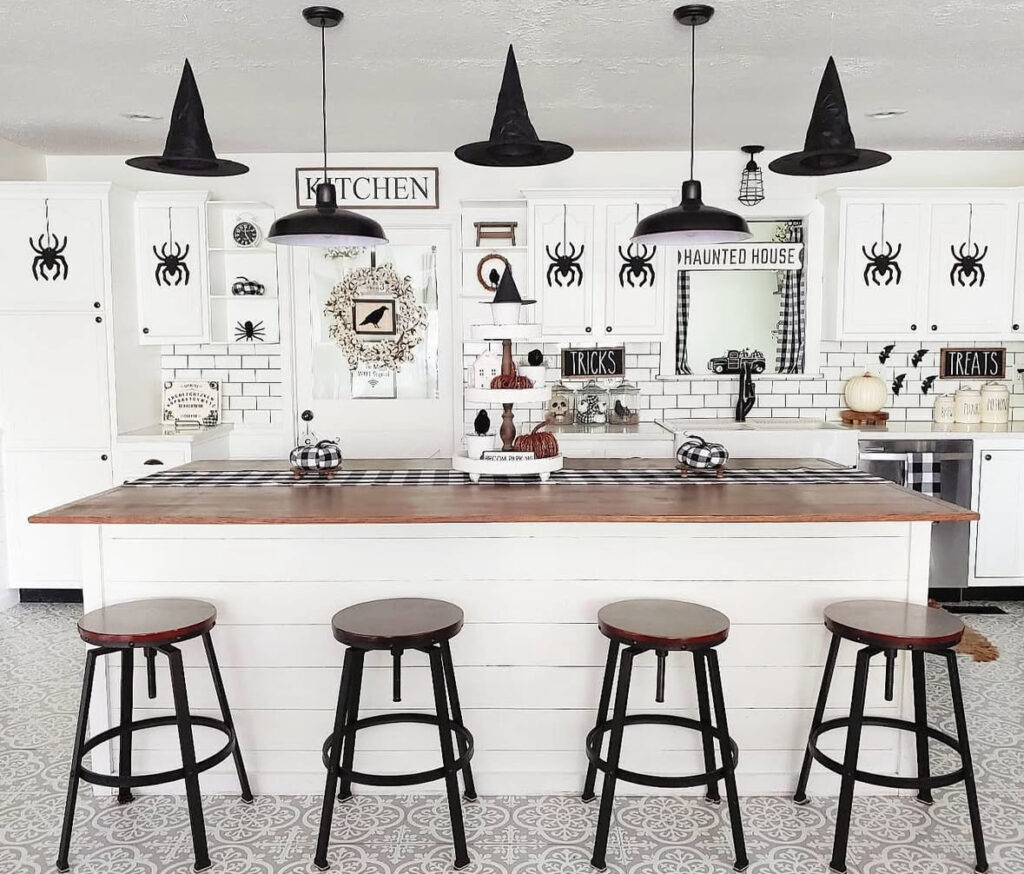 Floating black witch hats suspended over a kitchen island with a checkered table runner.