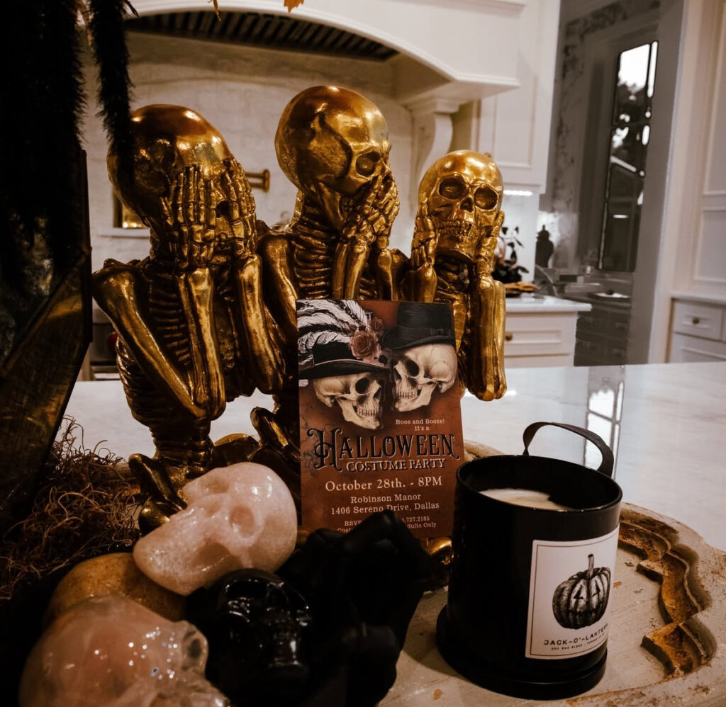 Gold skeleton figurines styled with a candle and party invite as a dramatic kitchen display.