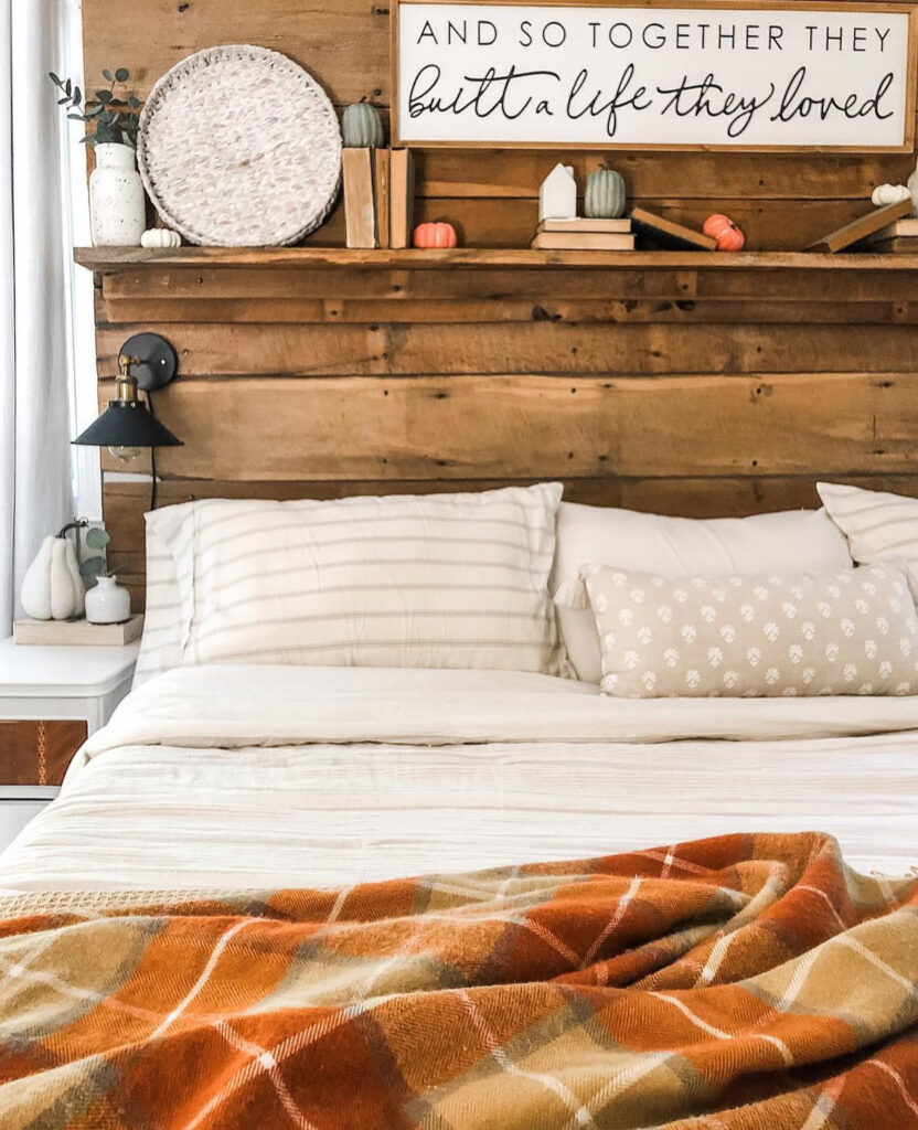 Rustic wood headboard shelf styled with tiny pumpkins, vintage books and plaid throw — DIY fall bedroom decor.