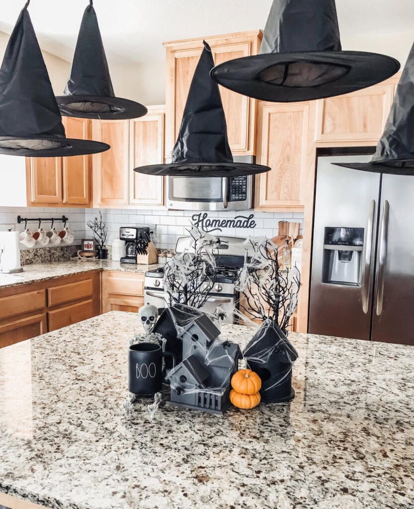 Mini haunted village centerpiece with cobwebs, tiny pumpkins, and a poseable skeleton on the kitchen island.
