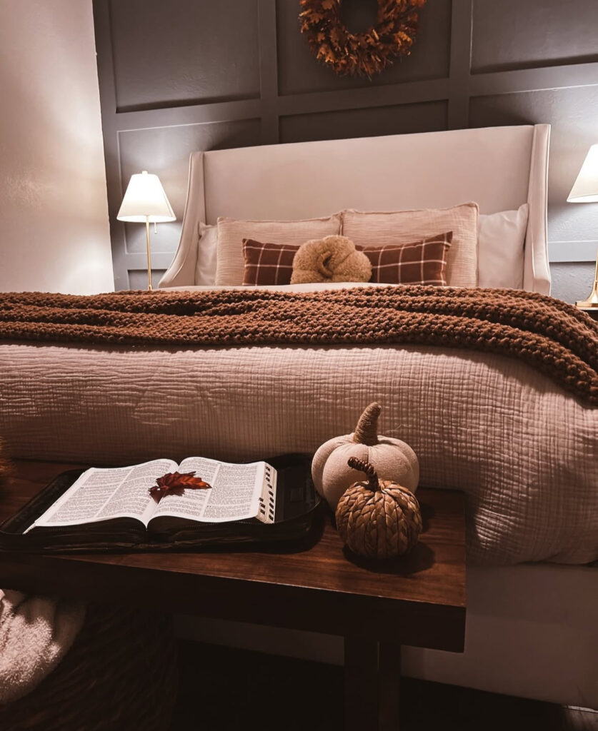 Paneled wall, chunky knit throw, plaid lumbar, wreath and pumpkins on bench — cozy fall bedroom ideas.