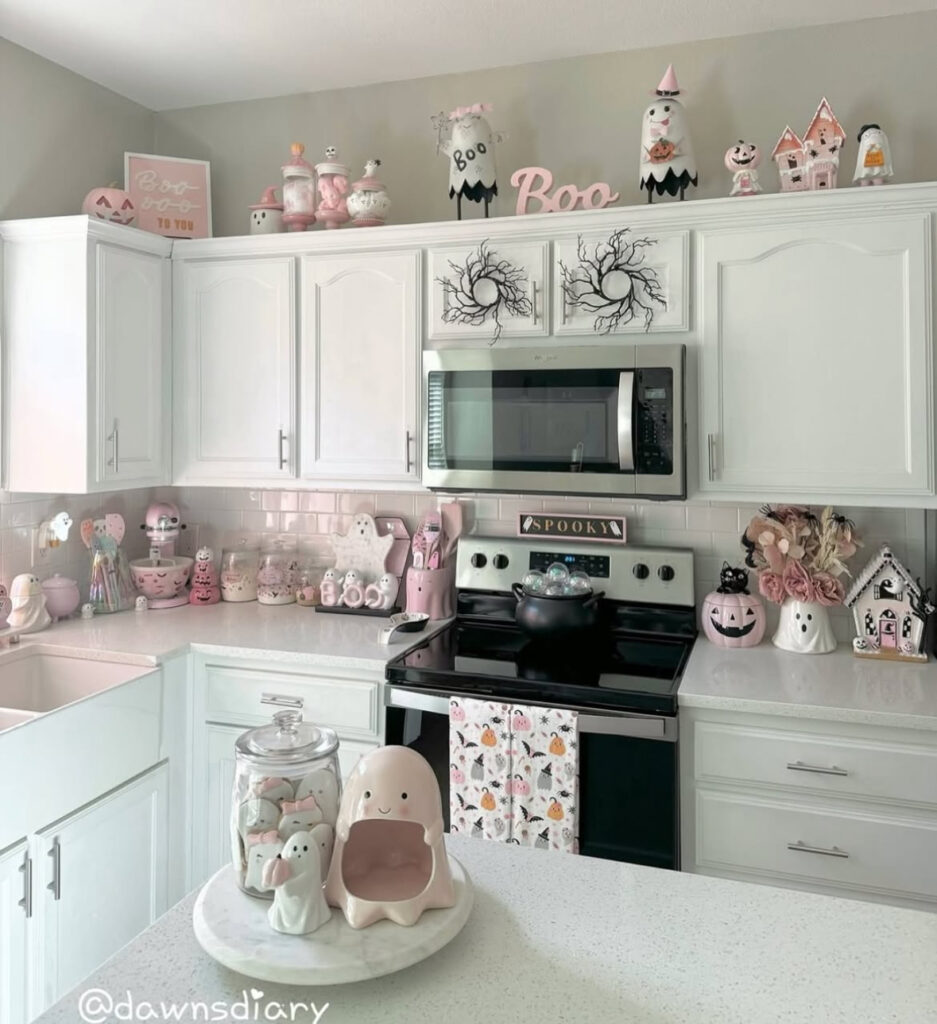 Pastel Halloween backsplash styling with smiling ghosts, candy jars, and small house figurines.
