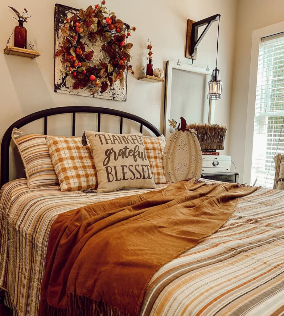 Farmhouse striped quilt, plaid pillows, “Thankful Grateful Blessed” pillow, fruit wreath and amber accents — autumn fall bedroom decor.