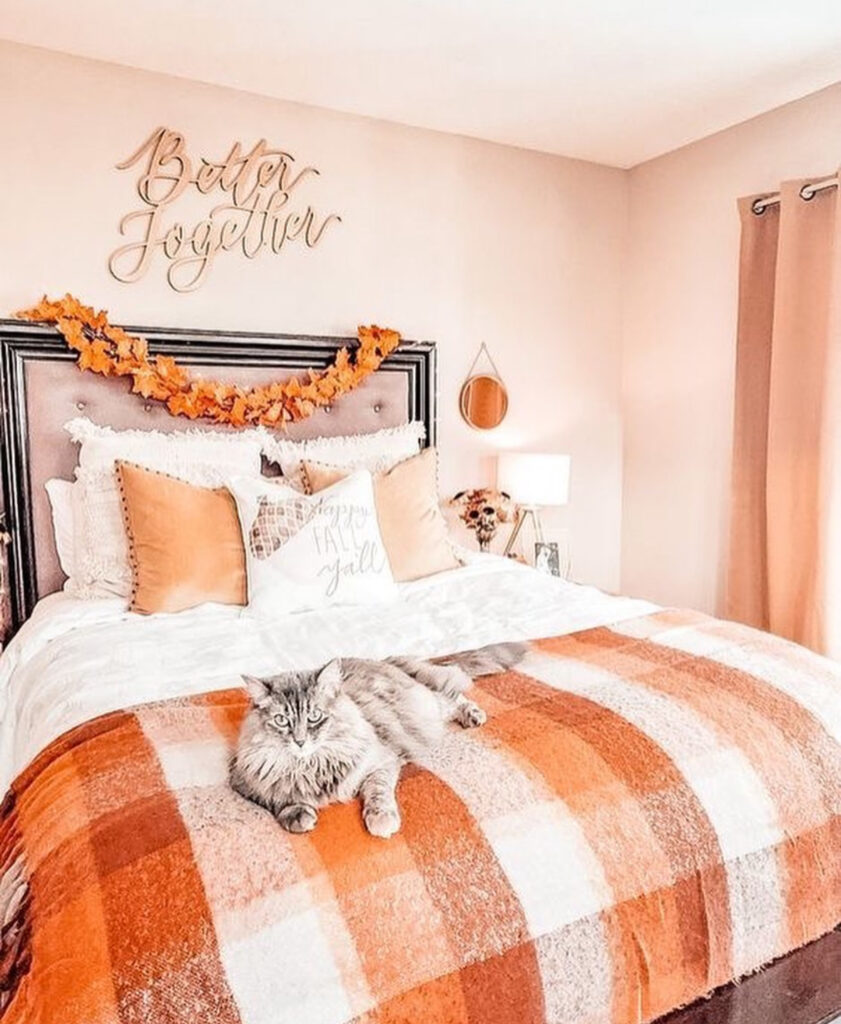 Cute fall bedroom with buffalo-check throw, leaf garland, script wall art and fluffy cat — cute fall bedroom ideas.