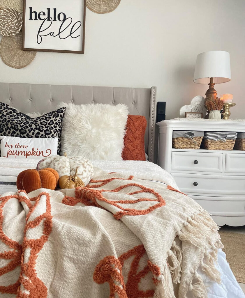 Neutral farmhouse bedroom with “hello fall” sign, leopard pillow, pumpkin throw and velvet pumpkins — cute fall decor ideas for bedroom.