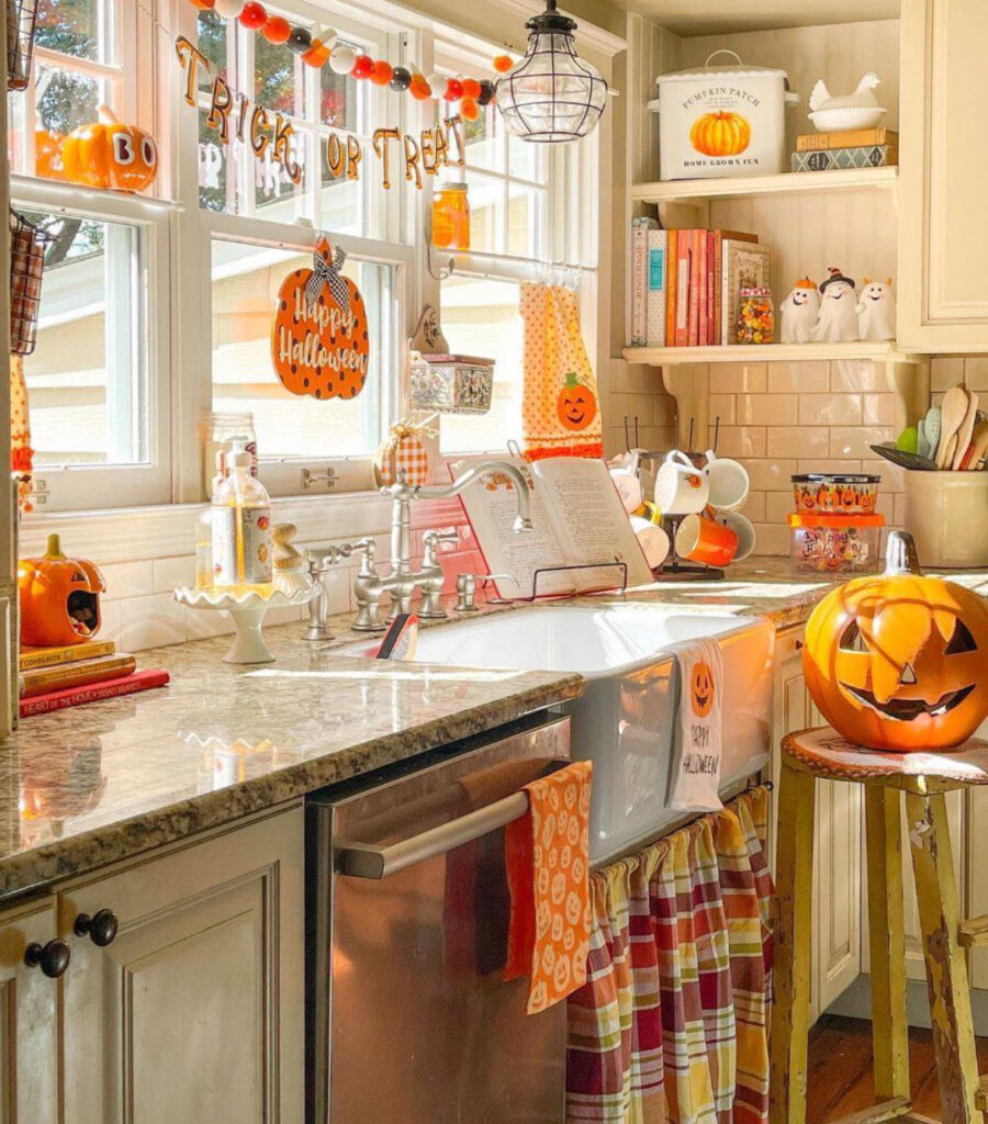 Sunny sink nook with “Trick or Treat” banner, orange linens, vintage accents, and pumpkins on the window ledge.