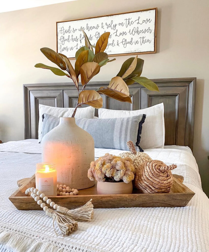 Cozy bed tray vignette with candle, ceramic vase, wood beads and woven pumpkins on white bedding — DIY fall bedroom decor ideas.