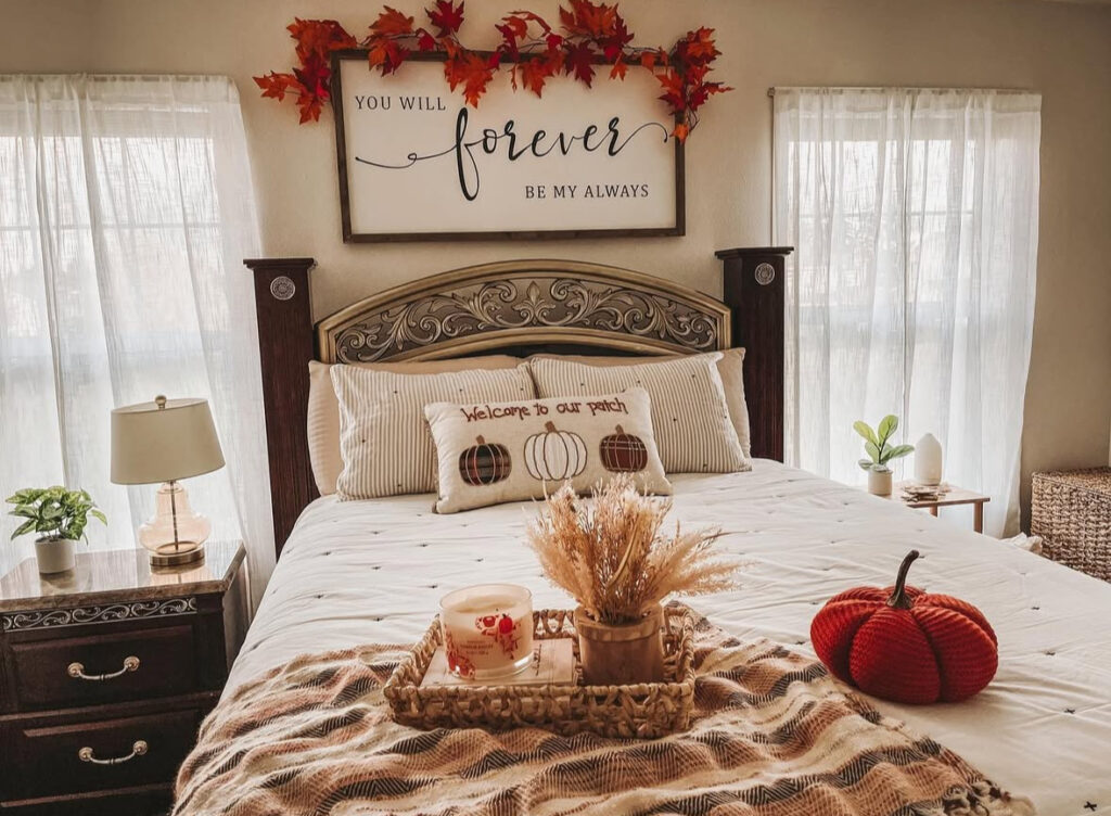 Traditional bed with leaf garland over sign, plaid pillows, woven tray and knit pumpkin — fall master bedroom ideas.