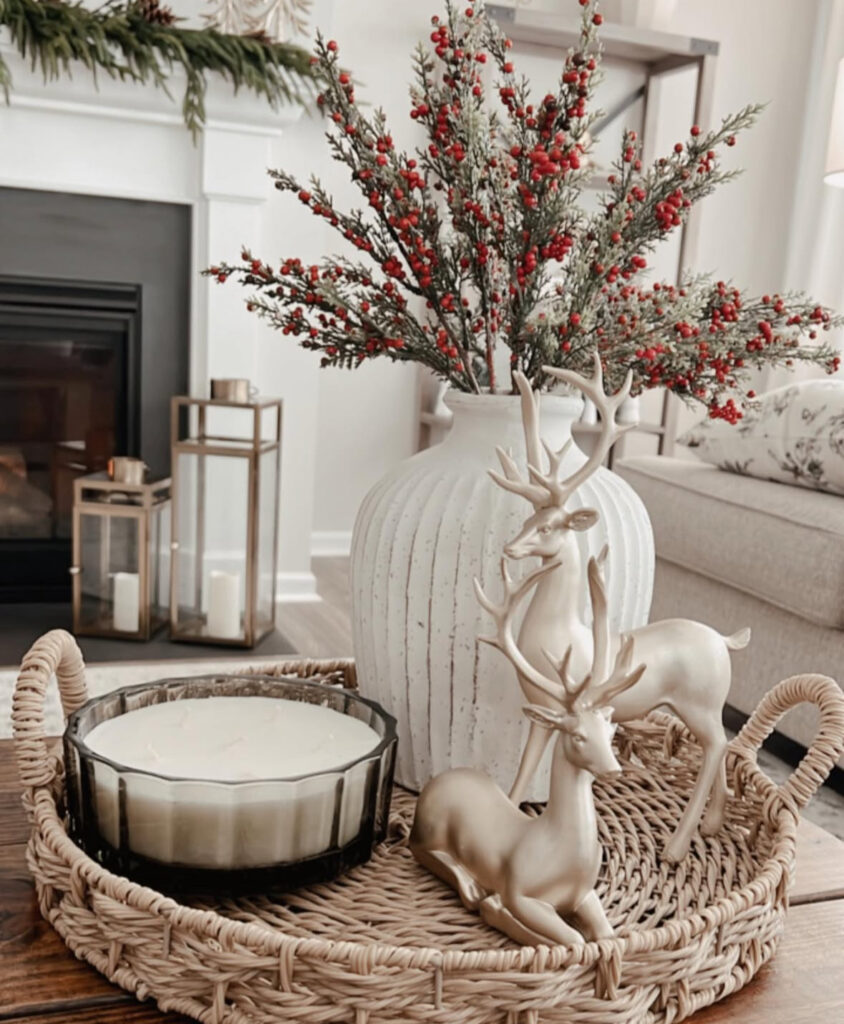 Woven tray styling with white ribbed vase of red berry stems, two gold deer figurines, and a multi-wick candle in smoky glass.