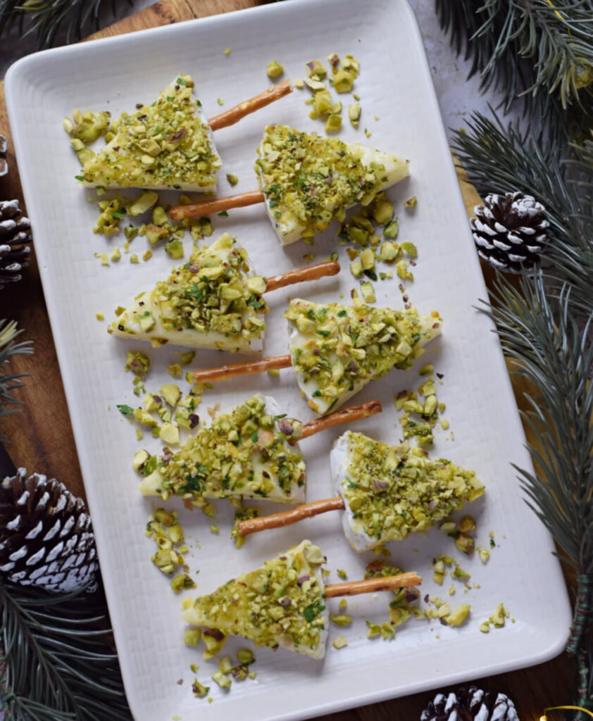 Triangles of brie on pretzel stick trunks, coated in chopped pistachios, arranged like little trees.