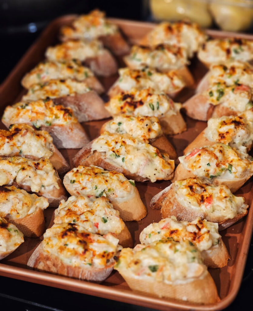 Sheet pan of baguette toasts piled with creamy chopped shrimp, broiled until golden and bubbly.