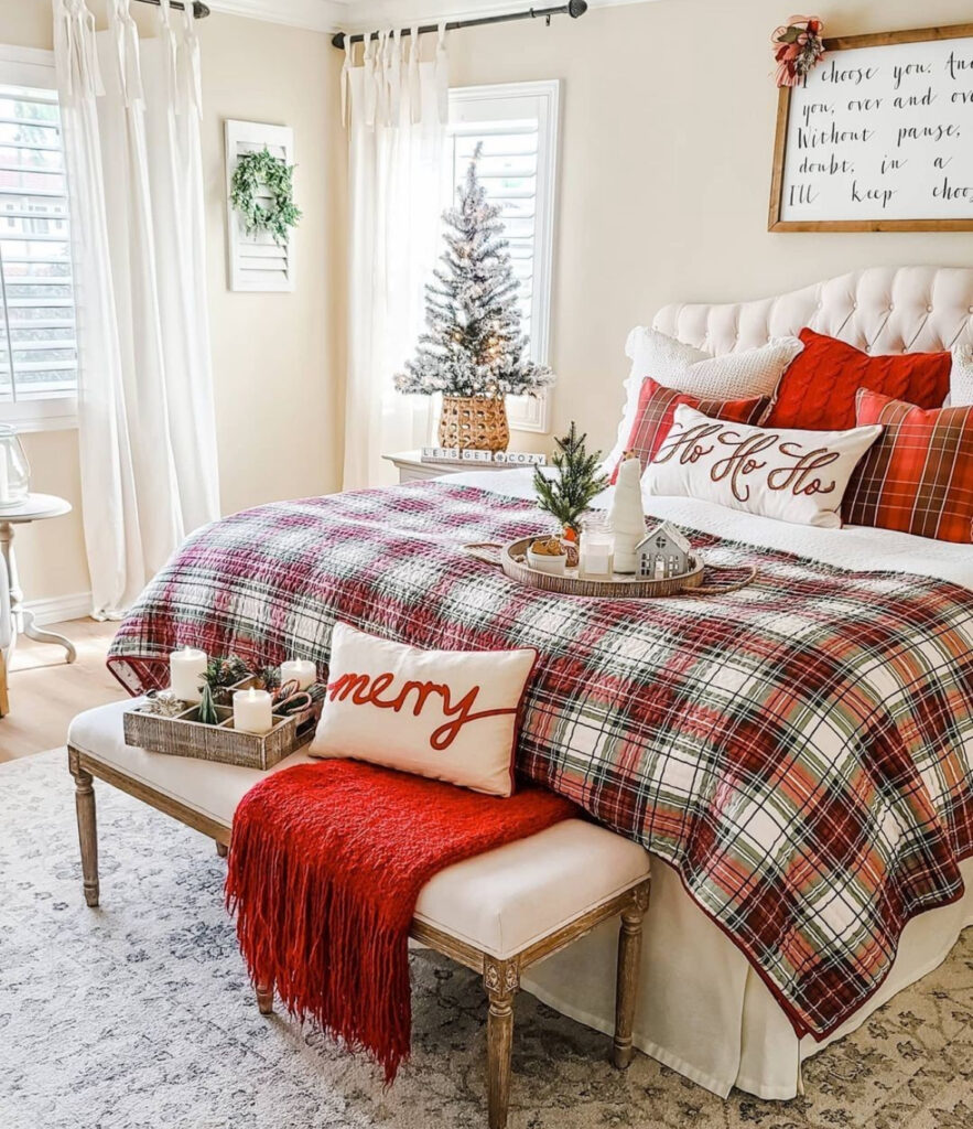 Red plaid quilt, “Ho Ho Ho” pillow, and bench styling—timeless Christmas bedroom decor ideas with traditional patterns. A small tree glows by the window.