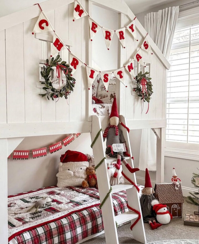Playhouse bunk beds decked with banners and elves—festive kids Christmas bedroom ideas. Plaid quilt and mini wreaths finish the look.