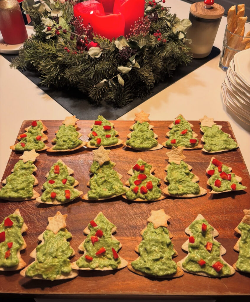 Tree-shaped crackers spread with bright green guacamole and dotted with red pepper “ornaments.”