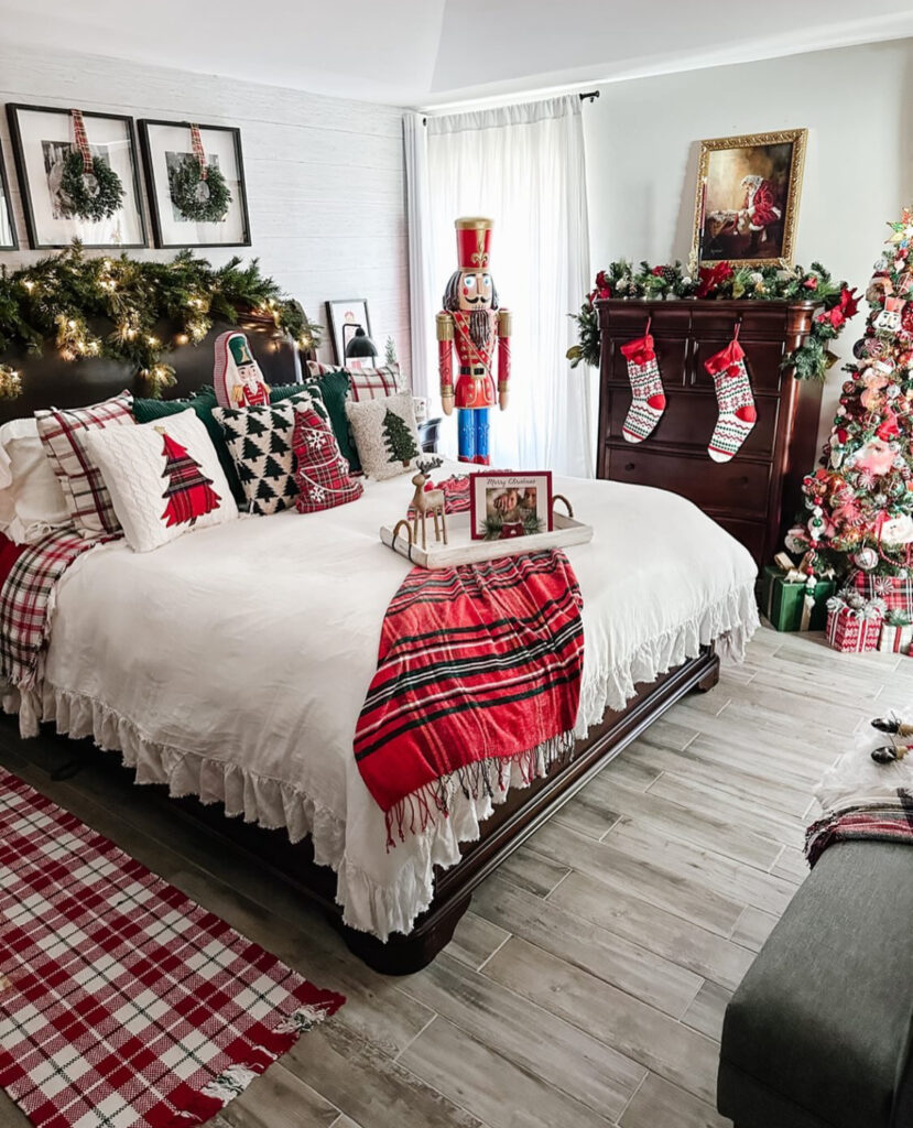 Headboard garland with twinkle lights and nutcracker accents—festive Christmas lights in bedroom ideas. Plaid textiles warm the white bedding.