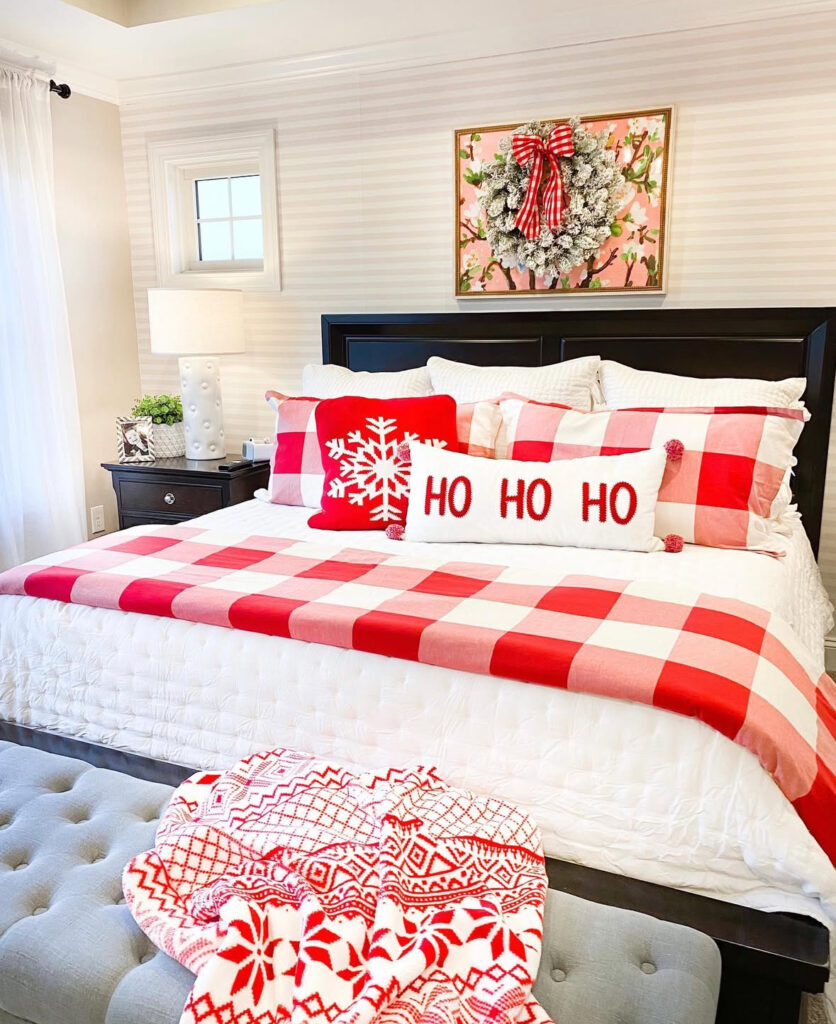 Red plaid quilt, “Ho Ho Ho” pillow, and bench styling—timeless Christmas bedroom decor ideas with traditional patterns. A small tree glows by the window.
