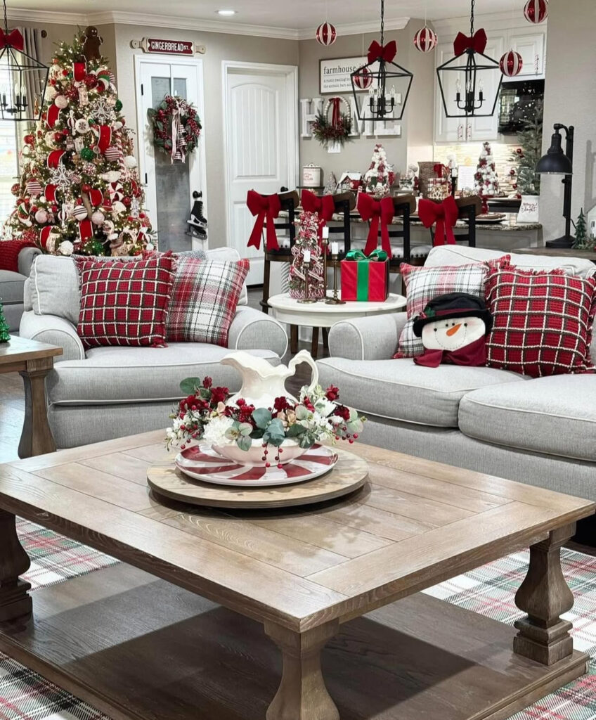 Festive living room with plaid pillows and candy-cane accents; wood coffee table holds layered trays with a pitcher and floral centerpiece.