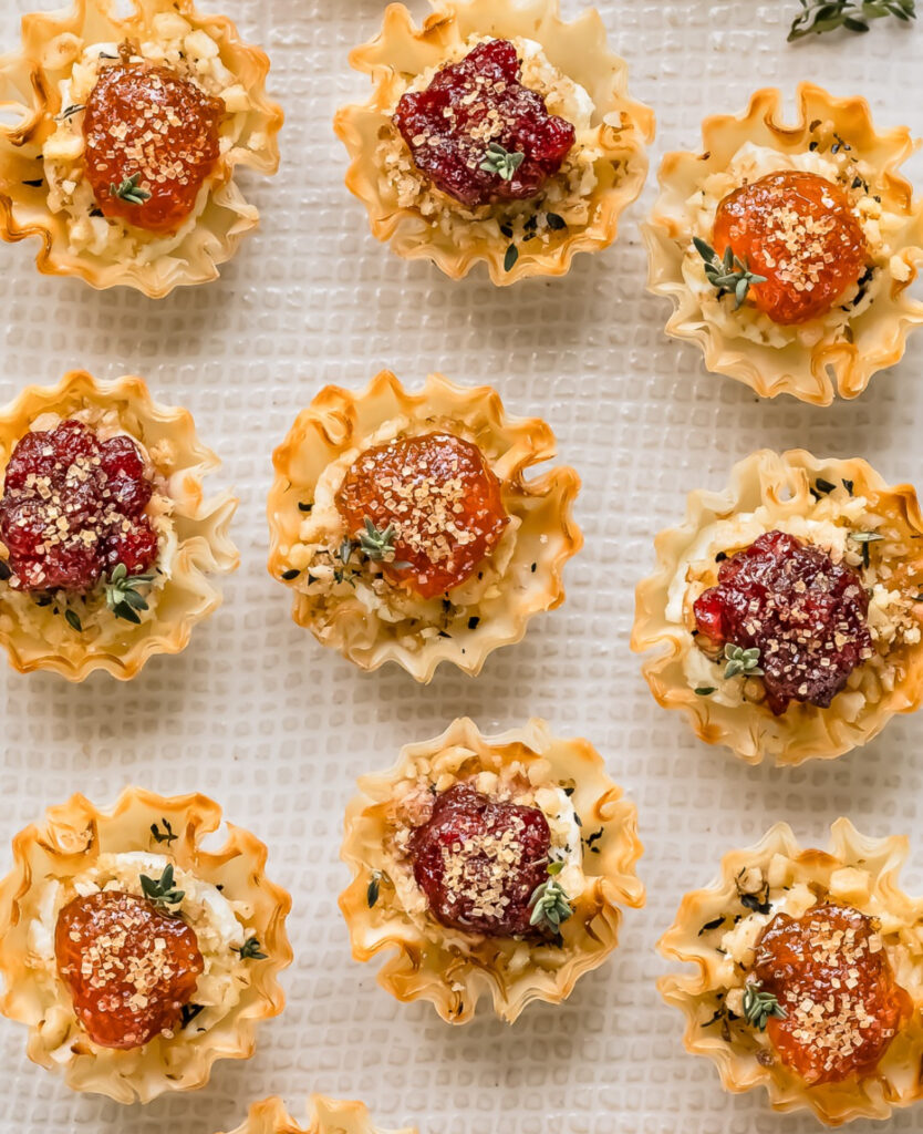Mini phyllo shells stuffed with goat cheese and finished with dollops of red or amber jam and herb flakes.
