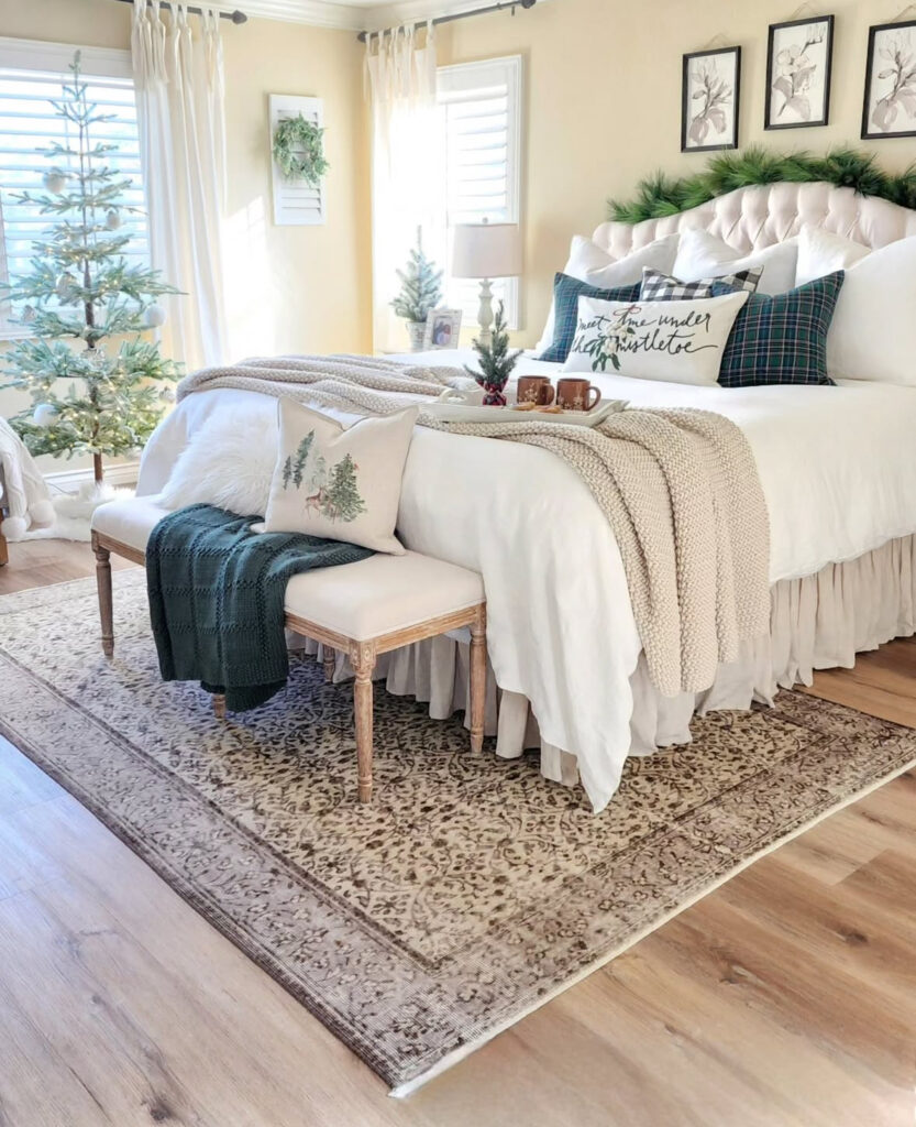 Light-filled room with flocked trees and knit throws—Christmas tree in bedroom ideas for a serene, neutral retreat. Garland crowns the headboard for a soft holiday touch.