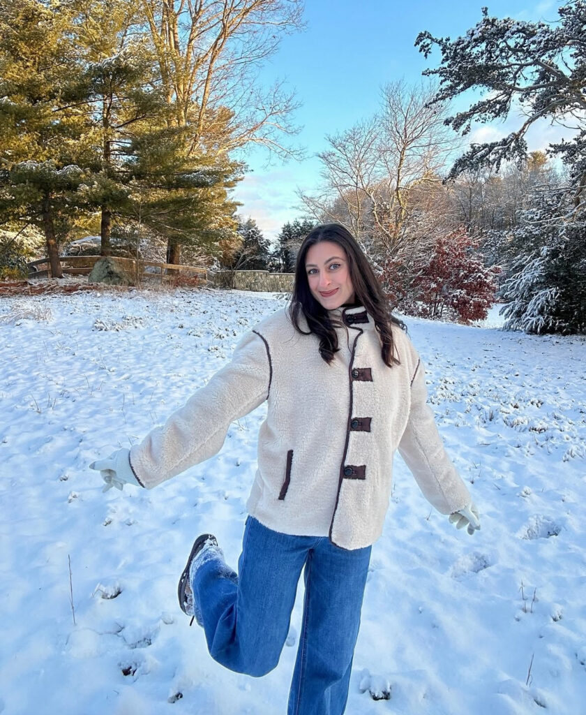 Boxy fleece with contrast trims and straight blue denim on a wooded trail in winter.