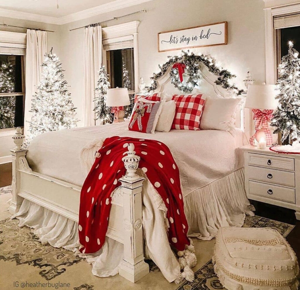 Grand white bed framed by lit trees and red accents—bold Christmas lights in bedroom ideas. Polka-dot throw adds playful vintage flair.