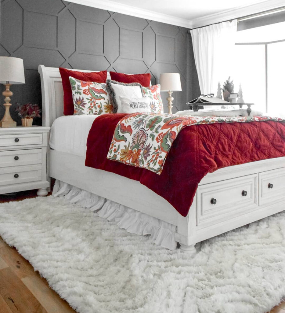 White bed with deep red velvet quilt and fluffy rug—simple, luxe Christmas bedroom decor ideas. Floral runner adds subtle color.
