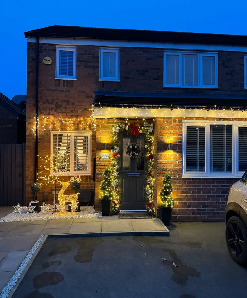 Front entry with icicle lights, topiary trees, and a glowing deer by the door.