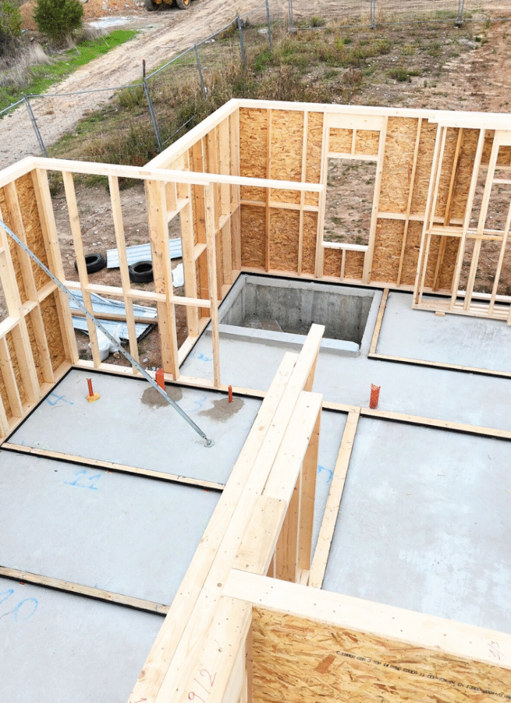 First floor framing with stair opening, kiln-dried studs and OSB sheathing on a concrete slab.