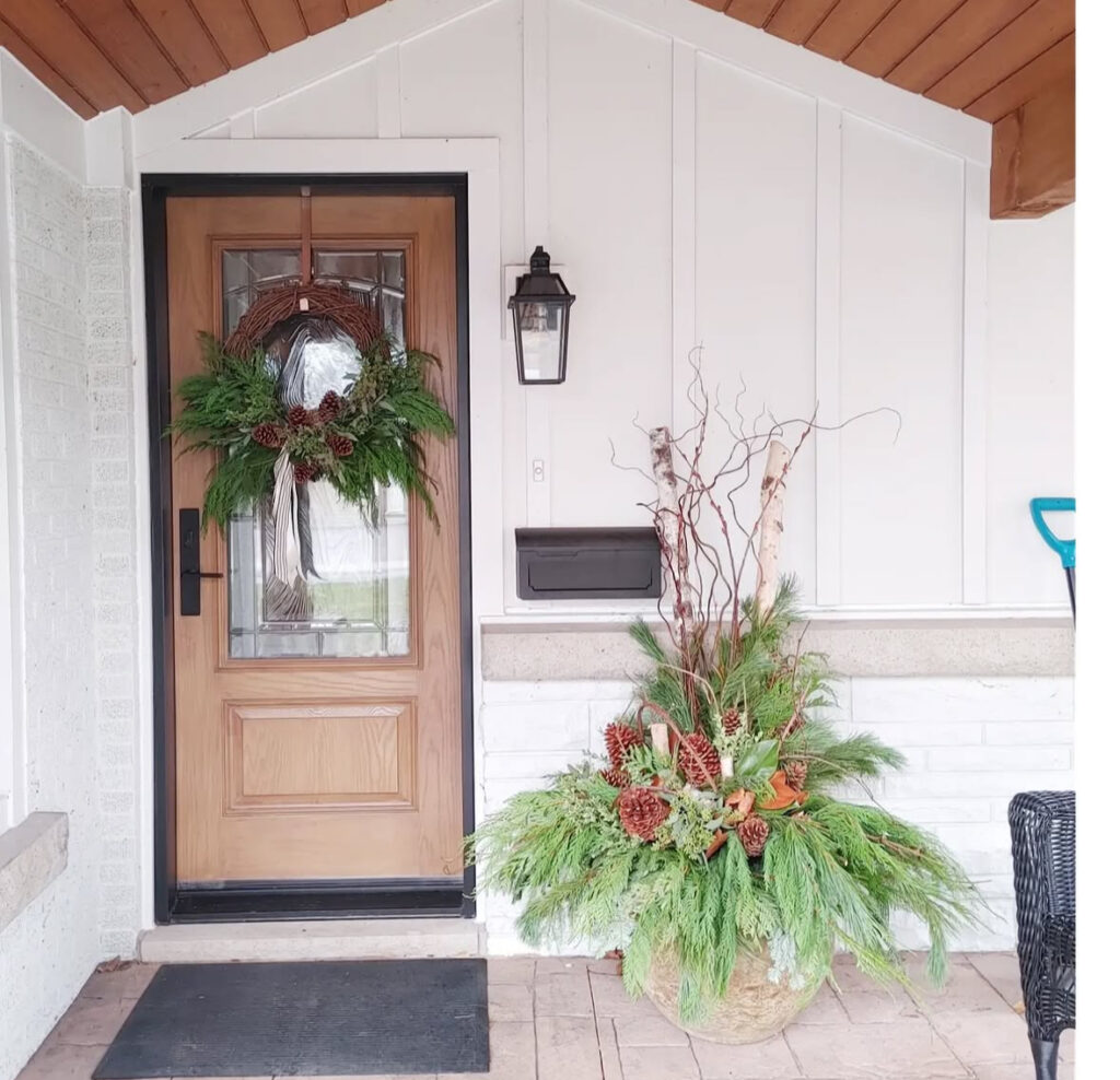 Birch poles and curly willow rising from a cedar skirt—refined Christmas outdoor planter ideas with natural height.
