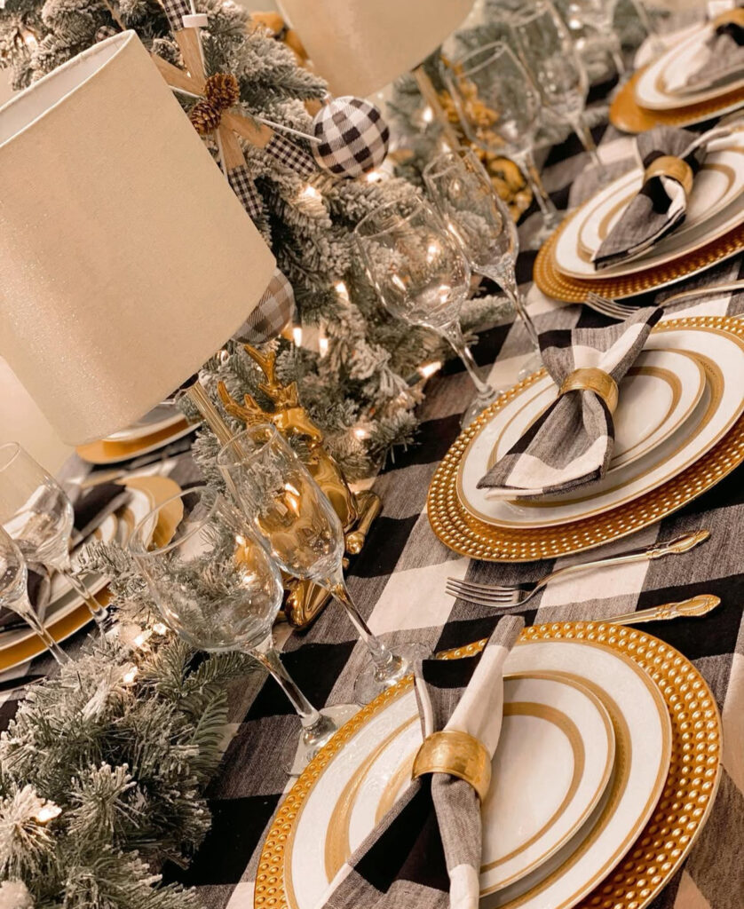 Buffalo check table with gold chargers and frosted garland lights.
