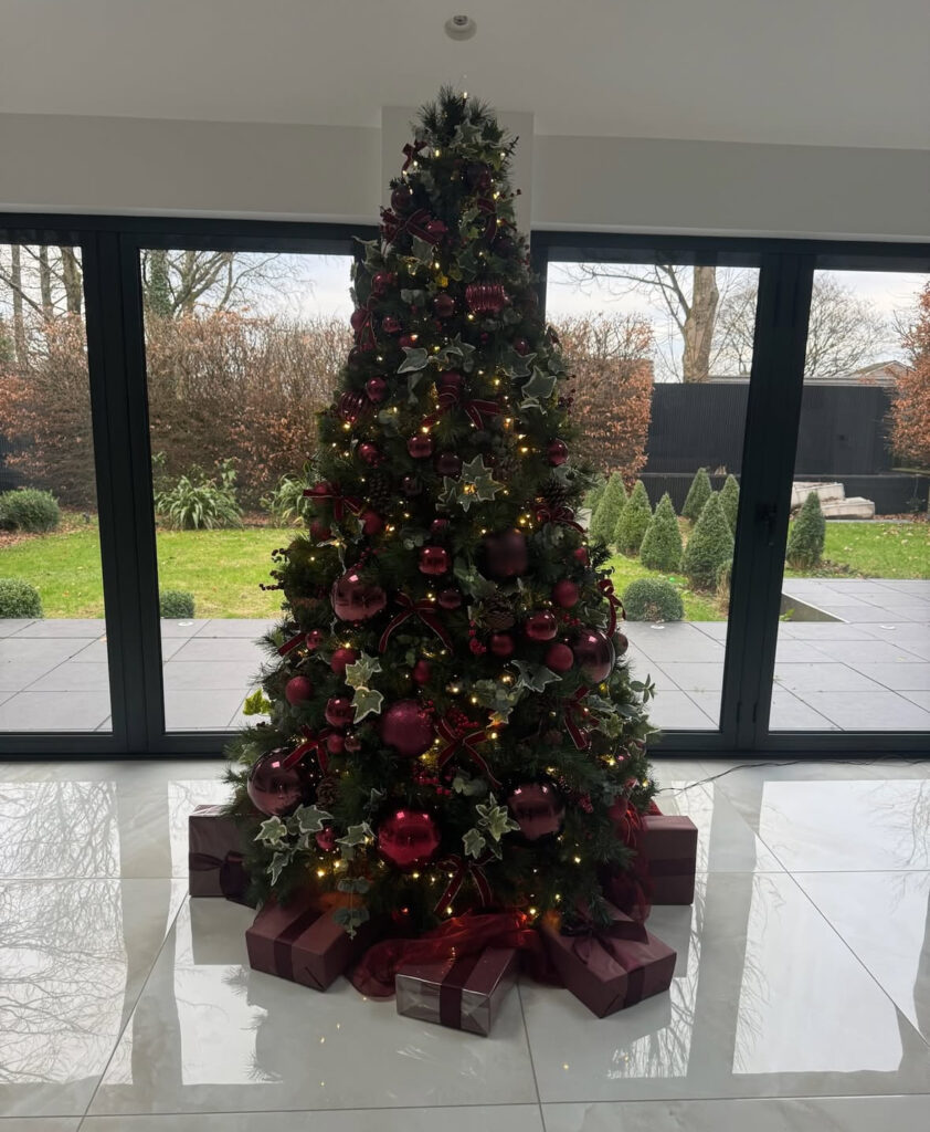 Classic burgundy Christmas tree with gold ornaments and warm sparkle