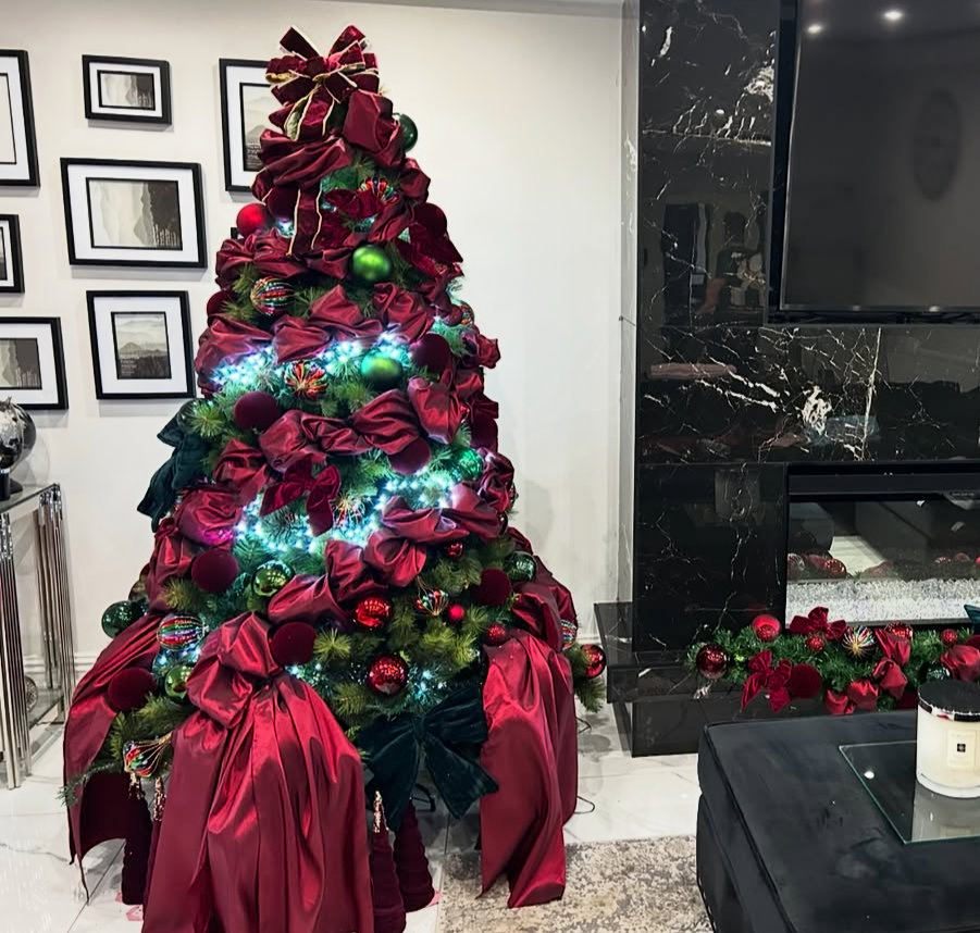 Modern living room with a burgundy Christmas tree decorated with couture bows
