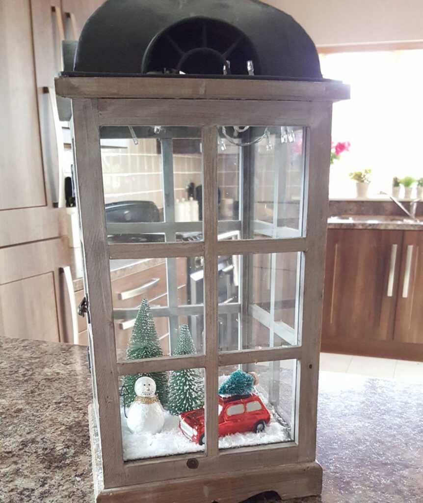 Snowy cabin scene inside a rustic winter lantern