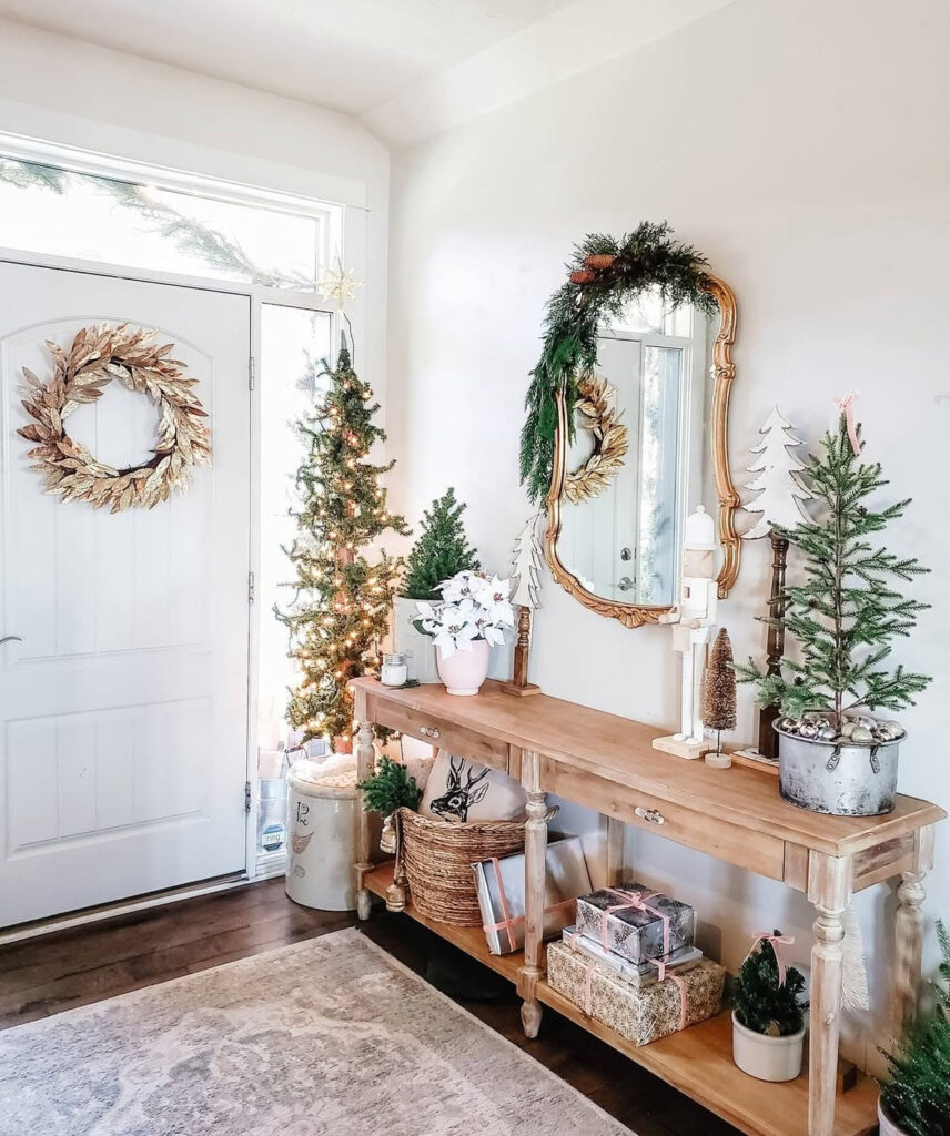 Gold mirror entryway decorated with warm Christmas lights and small tree trio