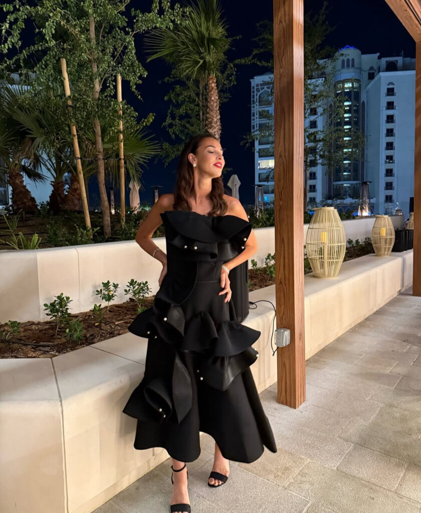 Off-shoulder ruffled black dress with pearl studs; sculptural new years eve outfits women will love.