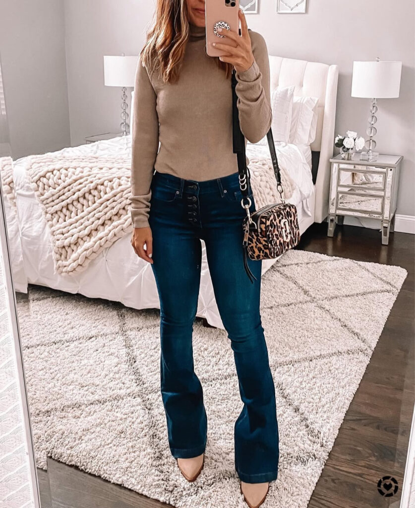 Woman walking through fall leaves in a cream buttoned shirt dress, white chunky boots, and a wide-brim hat.
