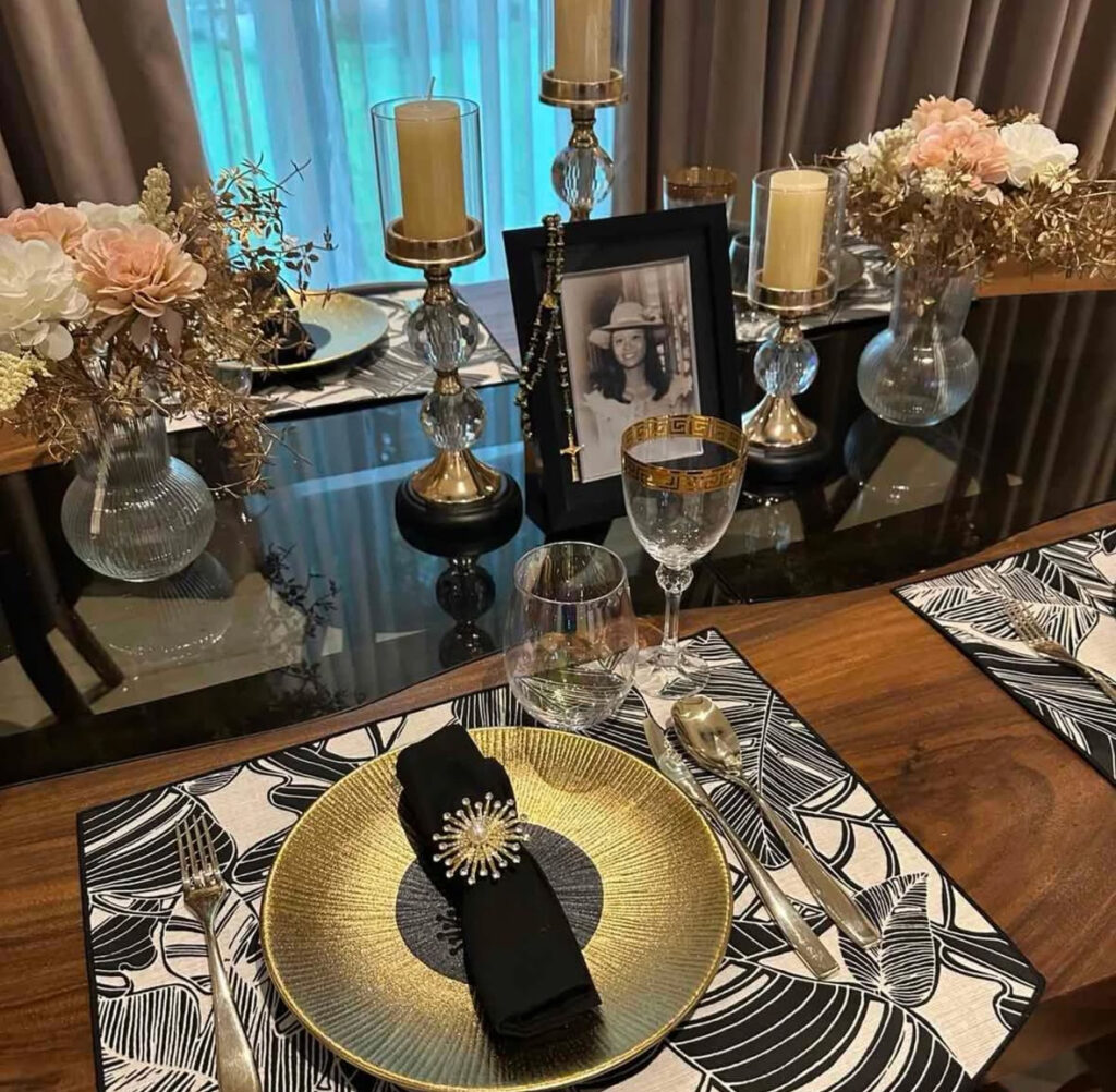 Modern black and gold place setting with florals and framed photo.