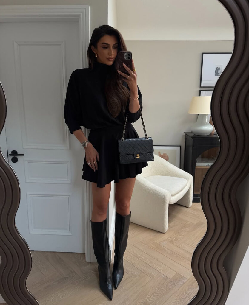 All-black knit mini, tall pointed boots, quilted shoulder bag; city-ready casual new years eve outfits.