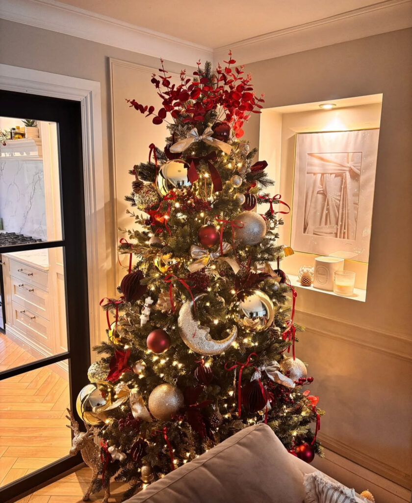 Glam burgundy Christmas tree glowing beside a modern kitchen