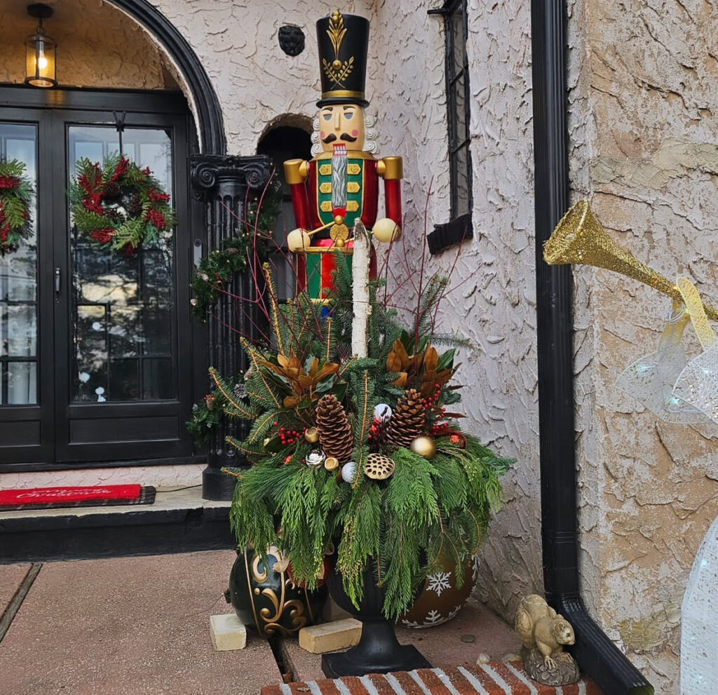 Towering urn with cascading cedar, magnolia, cones, and red twig dogwood—dramatic large Christmas planter ideas for big façades.