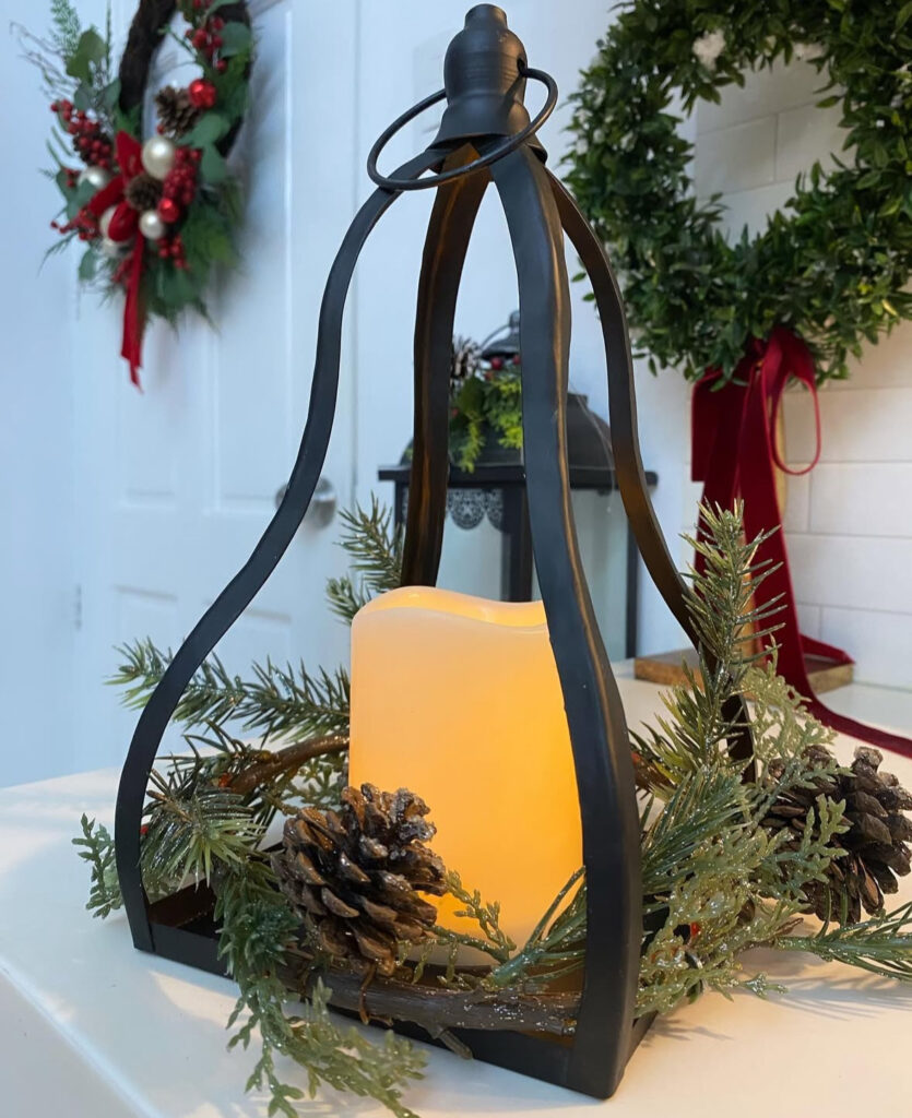Open-frame lantern glowing with pinecones and candles