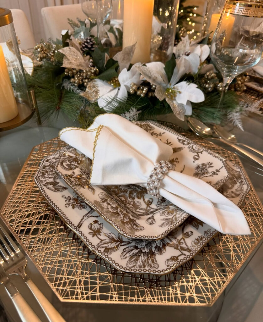 Patterned china stacked on geometric gold charger with pearl napkin ring.