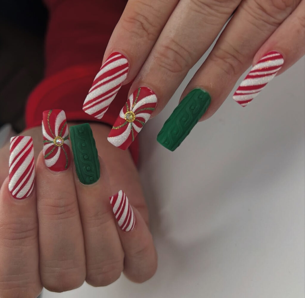 Red and white peppermint pinwheel nails with cozy knit texture