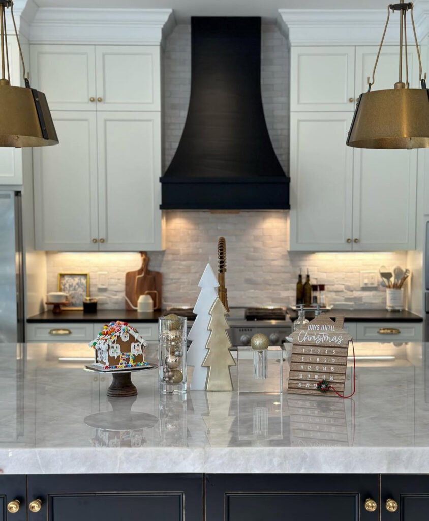 Marble island display with gingerbread house, metallic tree, ornament cylinder, and countdown sign.