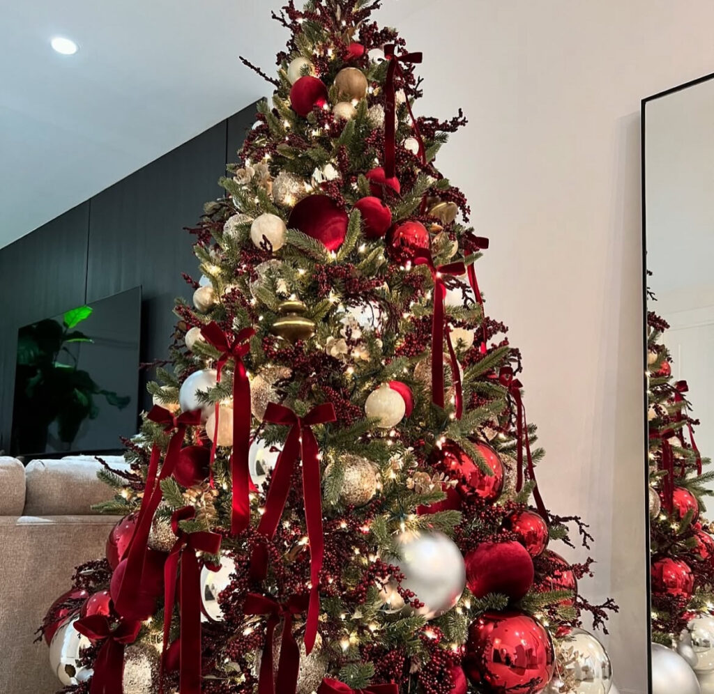 Burgundy Christmas tree with ribbon trails reflecting in a wall mirror