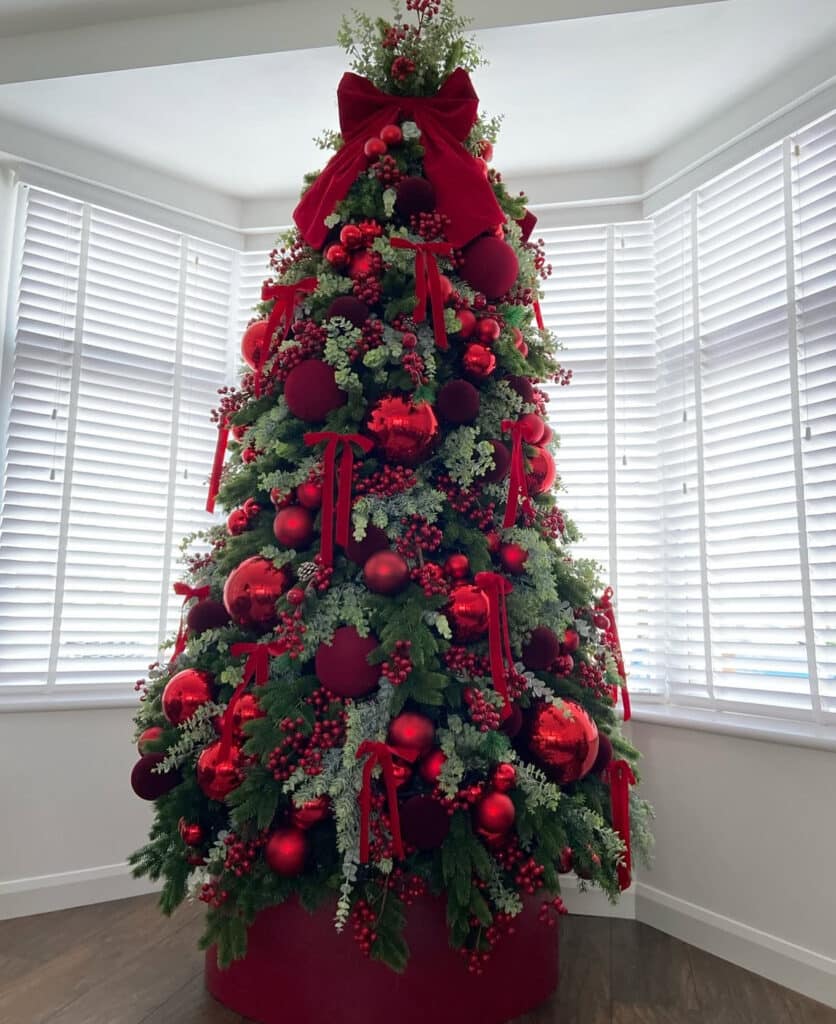 Bay window burgundy Christmas tree decorated with cascading ribbons