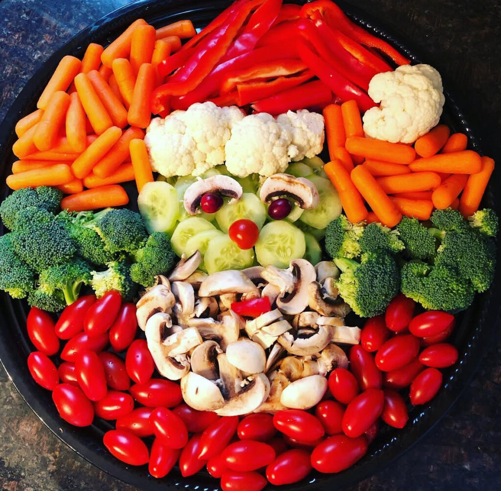 Santa face veggie platter with mushrooms for a beard, cucumbers for cheeks, and cherry tomatoes and peppers for bright accents.